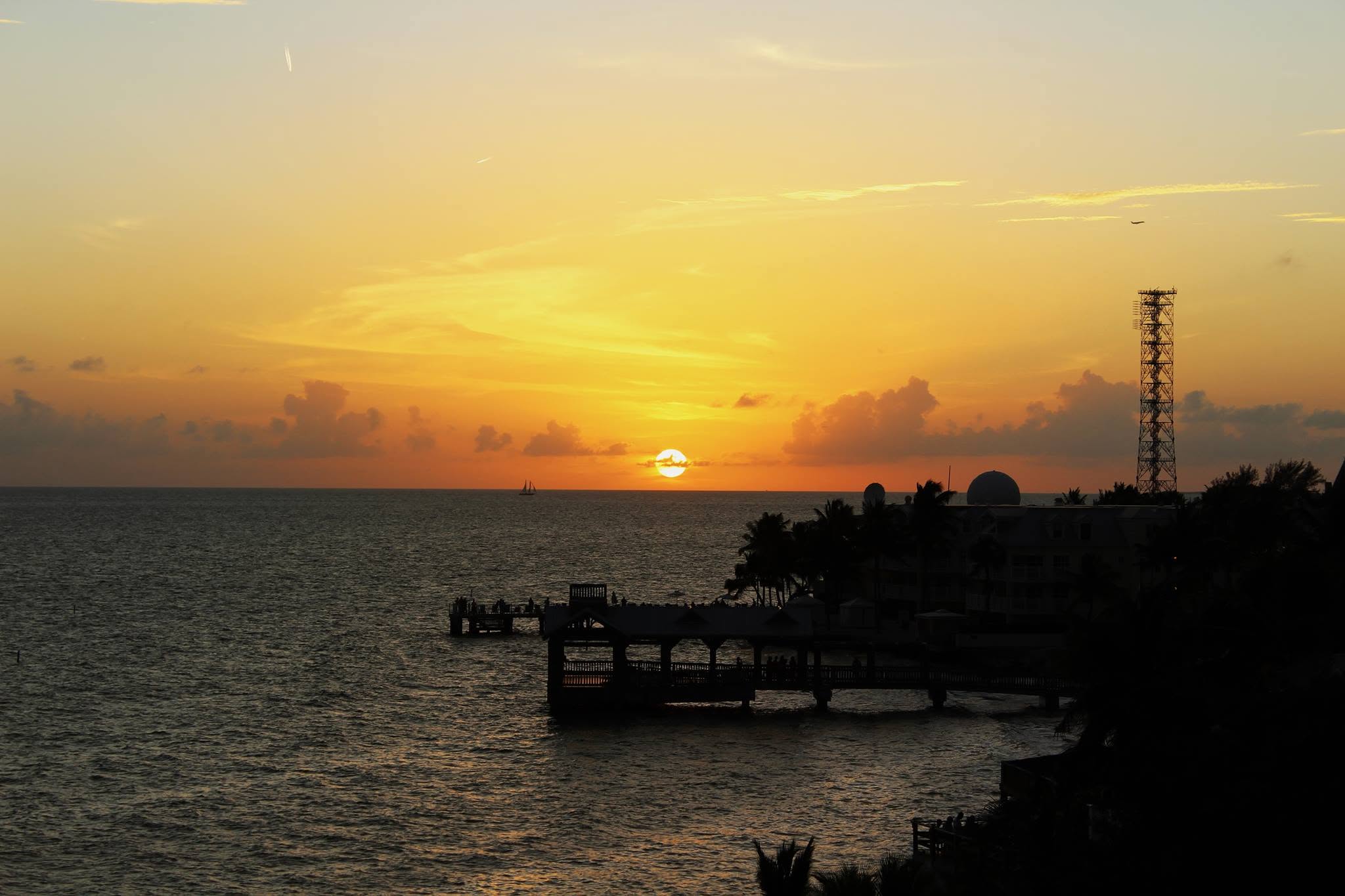 Sunset over the water at Key West, the pier and the town in silhouette.